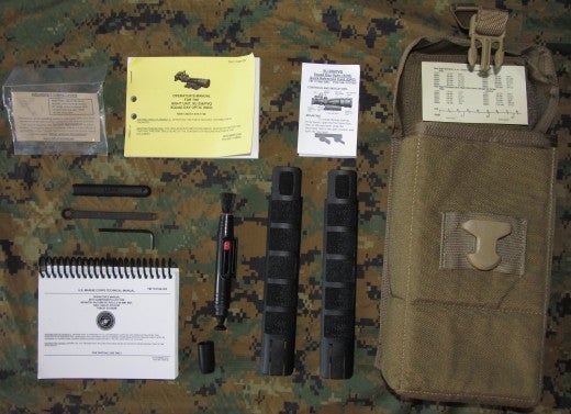 Trijicon SDO gear pouch with accessories. The gear bag is manufactured by Eagle Industries and is issued with every M27. Marine Corps T M 11758A-OR for the SDO/RMR and TM11810A-OR for the M27 are displayed top and bottom respectfully. M27 wrench is shown disassembled to left of SDO Lens Pen. Left of bag are H&K rail protectors. Extra pamphlets are data tables, SDO care guides and LaRue Tactical throw mount lever care information.